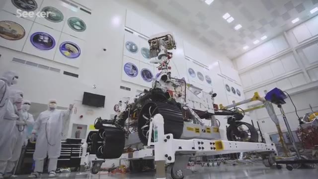 Mars rover in a clean room with engineers in white suits