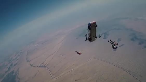 Skydivers falling beside a car