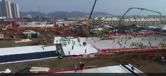 Aerial view of crews laying out the Huoshenshan hospital site with cranes and rows of workers