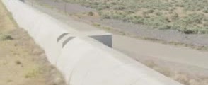 A long concrete beam tube running across dry scrubland