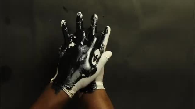 White gloves with black paint covering the palms and some fingers but leaving patches unpainted