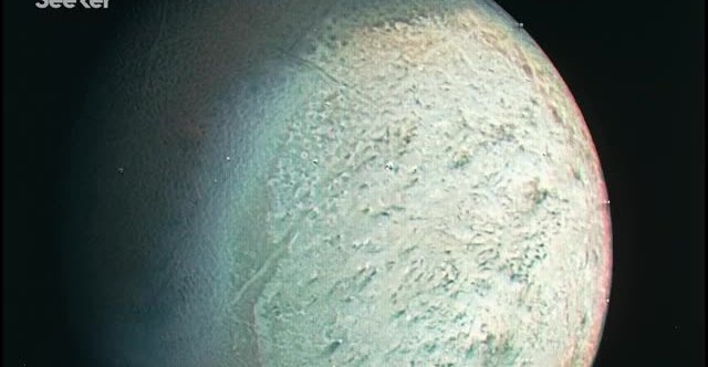 An icy moon filling the frame, pale green and cracked, against black space.