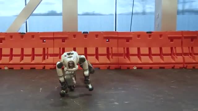 A humanoid robot crouched on a lab floor.