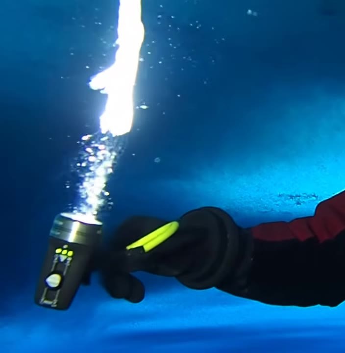 Diver lighting a brinicle forming under Antarctic sea ice