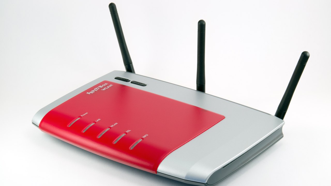 A red and silver wireless router with three black antennas on a white background.