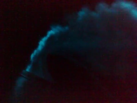 A blue-white plasma glow clinging to a dark structure at night.