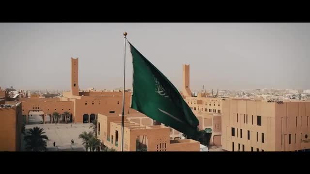 A green flag over sand-colored buildings.
